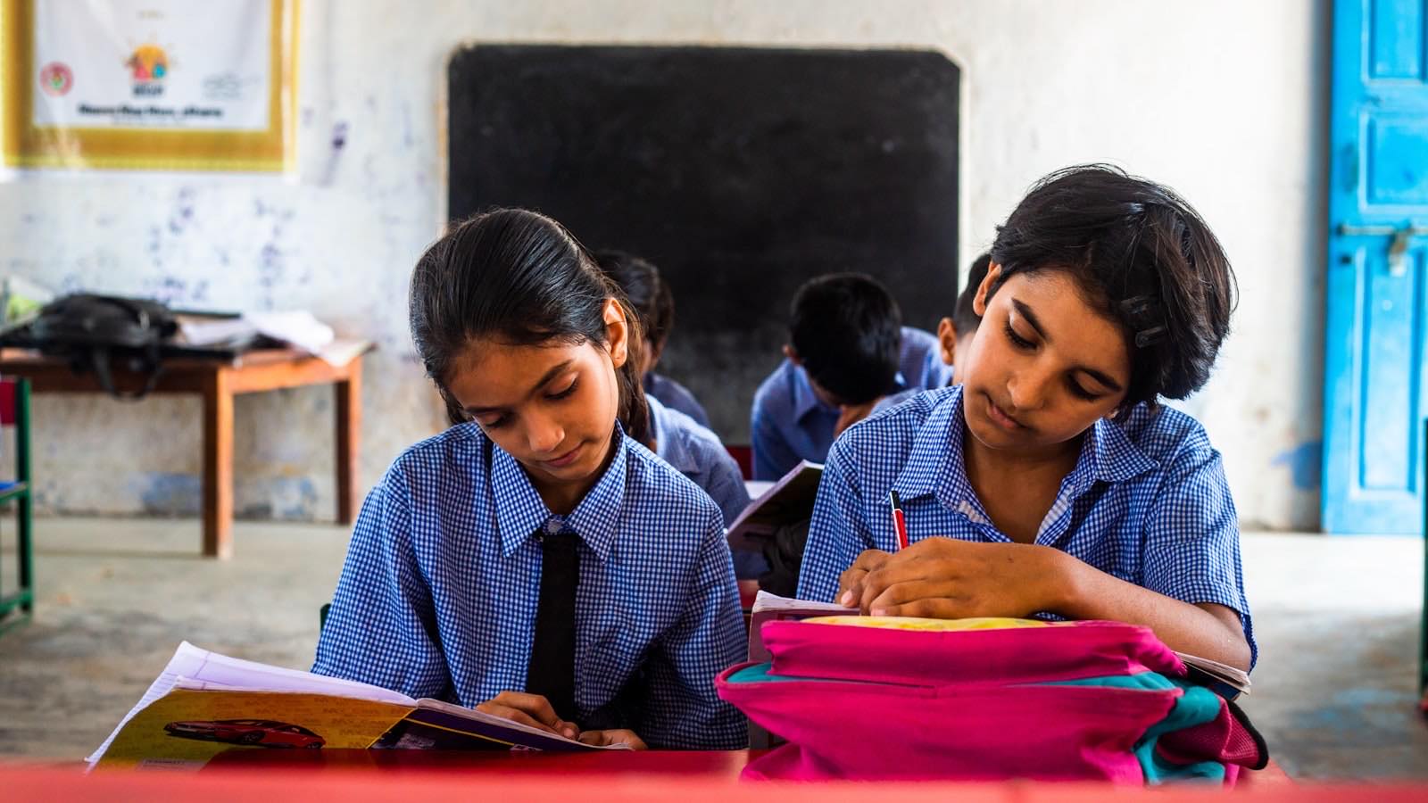 School students studying together at a desk in a classroom